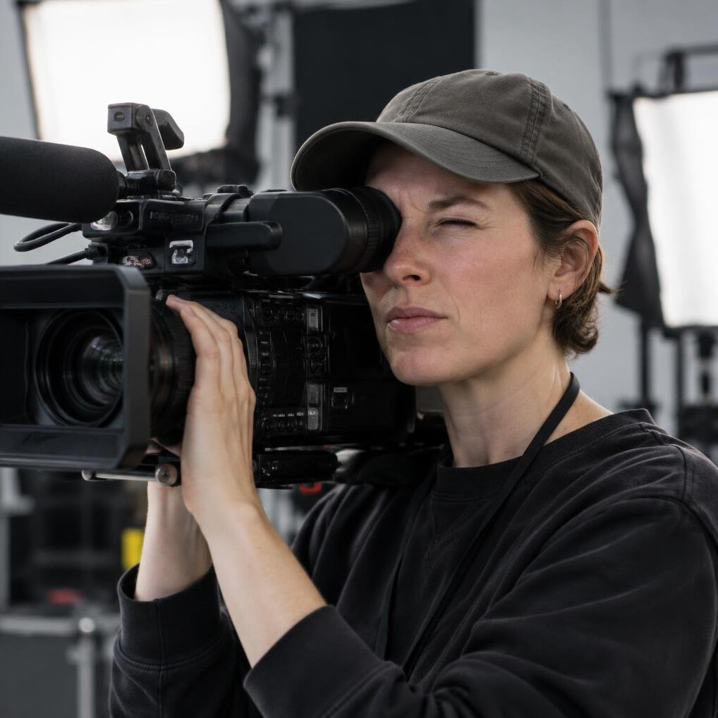Camera operator looking through a viewfinder on set